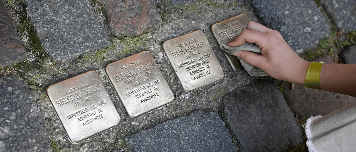KI-gneriertes Bild: Perosn putzt einen Stolperstein auf der Straße
